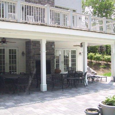 covered paved patio with new deck over a stone fireplace